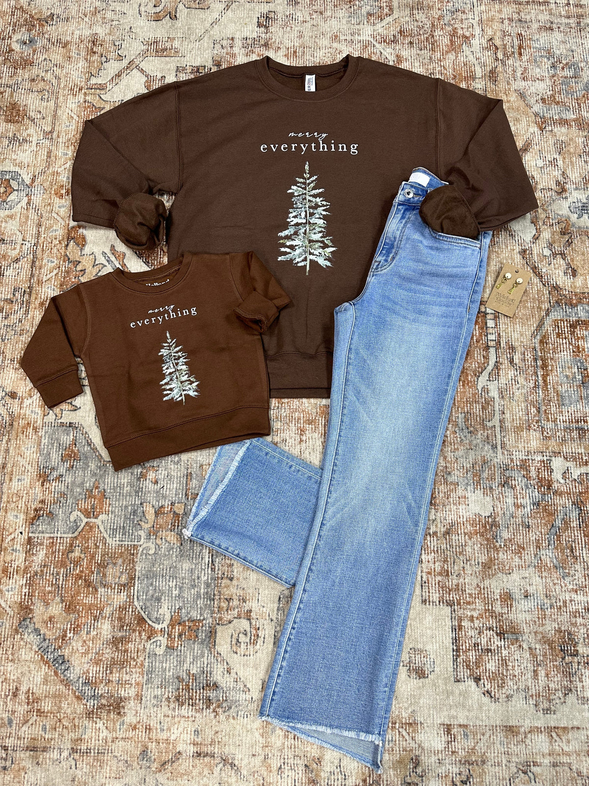 Brown sweatshirts with white graphic design and blue jeans on a textured surface